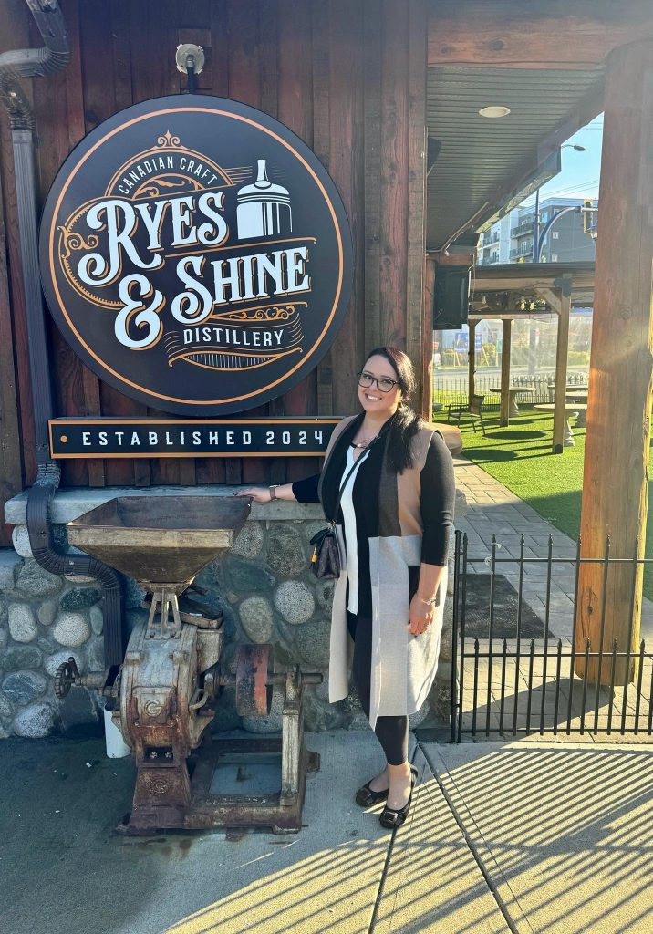 A team member beside the Ryes & Shine distillery sign